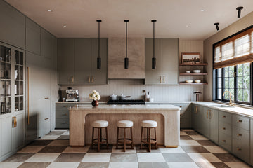 Three black cylindrical pendant lights evenly spaced above a light wood kitchen island with a white countertop.