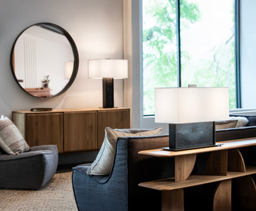 OPL two illuminated table lamps on a sofa table and wood console in a contemporary living room.