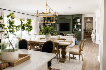 Ocean Pacific Lighting Visual Comfort Signature Darlana Grande Two Tier Chandelier for modern farmhouse foyer lighting above a wood dining table in a refined open-concept home with green built-ins, natural wood flooring, and layered neutral decor.