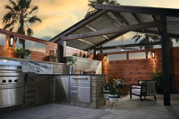 OPL covered outdoor kitchen and patio with wall lights, a ceiling fan and warm layered lighting at sunset.